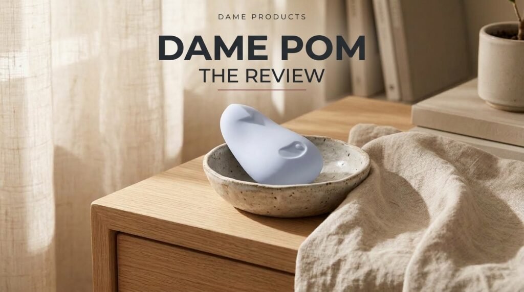 Dame Pom review featured image featuring Dame Products brand typography, Pom Review headline, and ice-blue palm vibrator on an oak bedside table