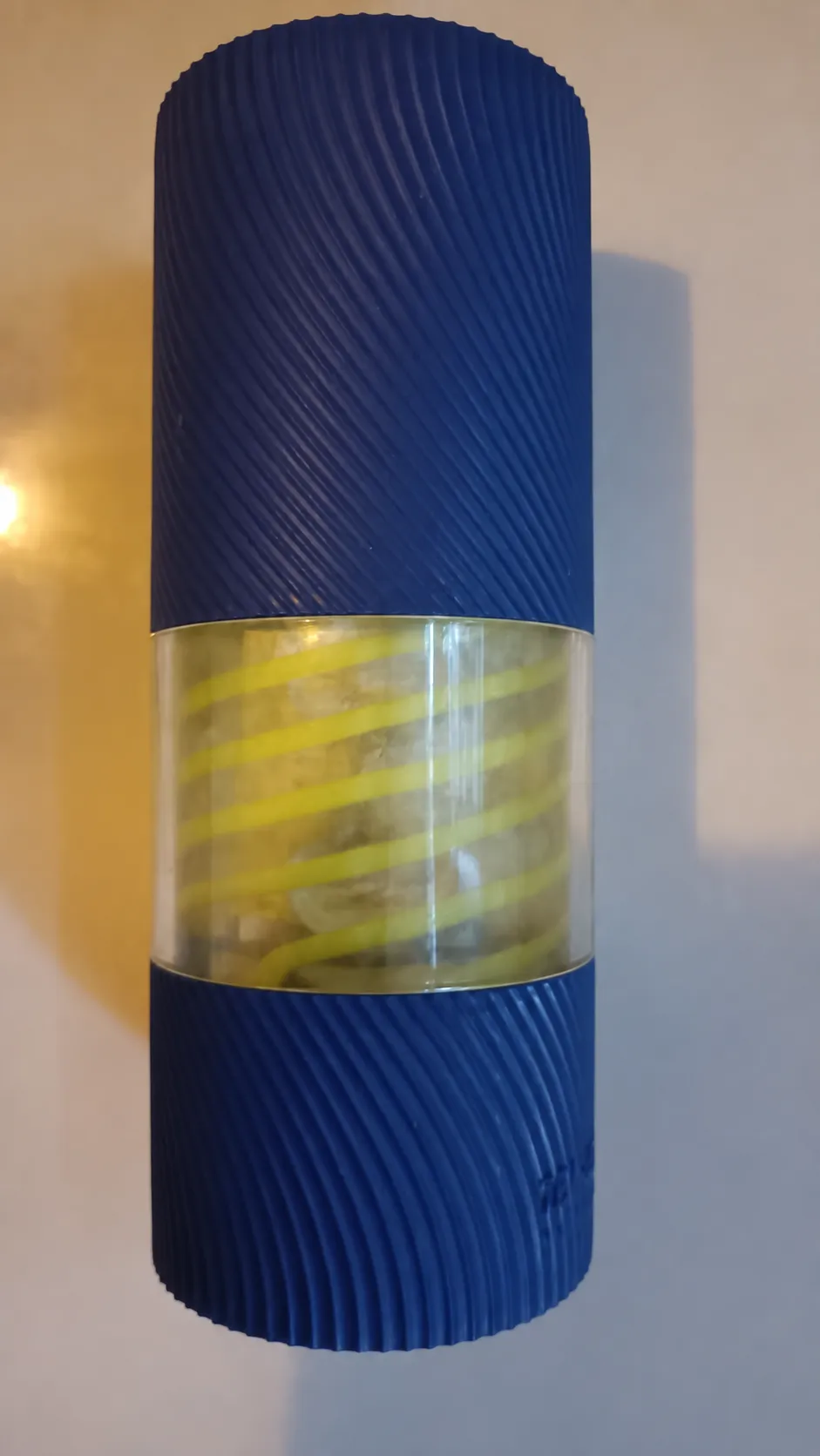 Close-up of the TENGA Spinner standing upright in its casing showing the internal yellow spiral coil through the clear window.